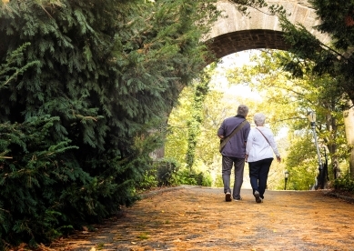 Couple walking on leaf covered path in park